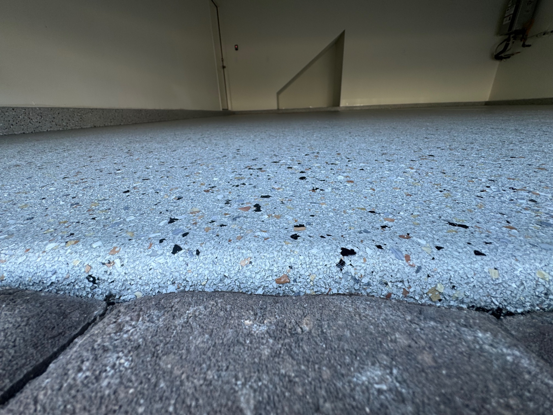 Light gray flake coating on a patio next to stone pavers